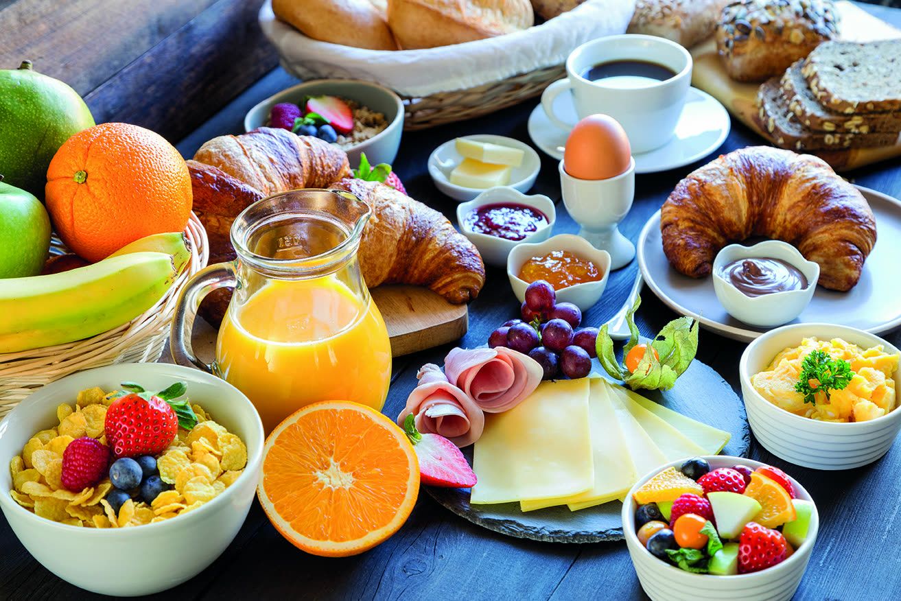 Frühstücksbuffet mit Croissants, Obst, Müsli und frischem Saft