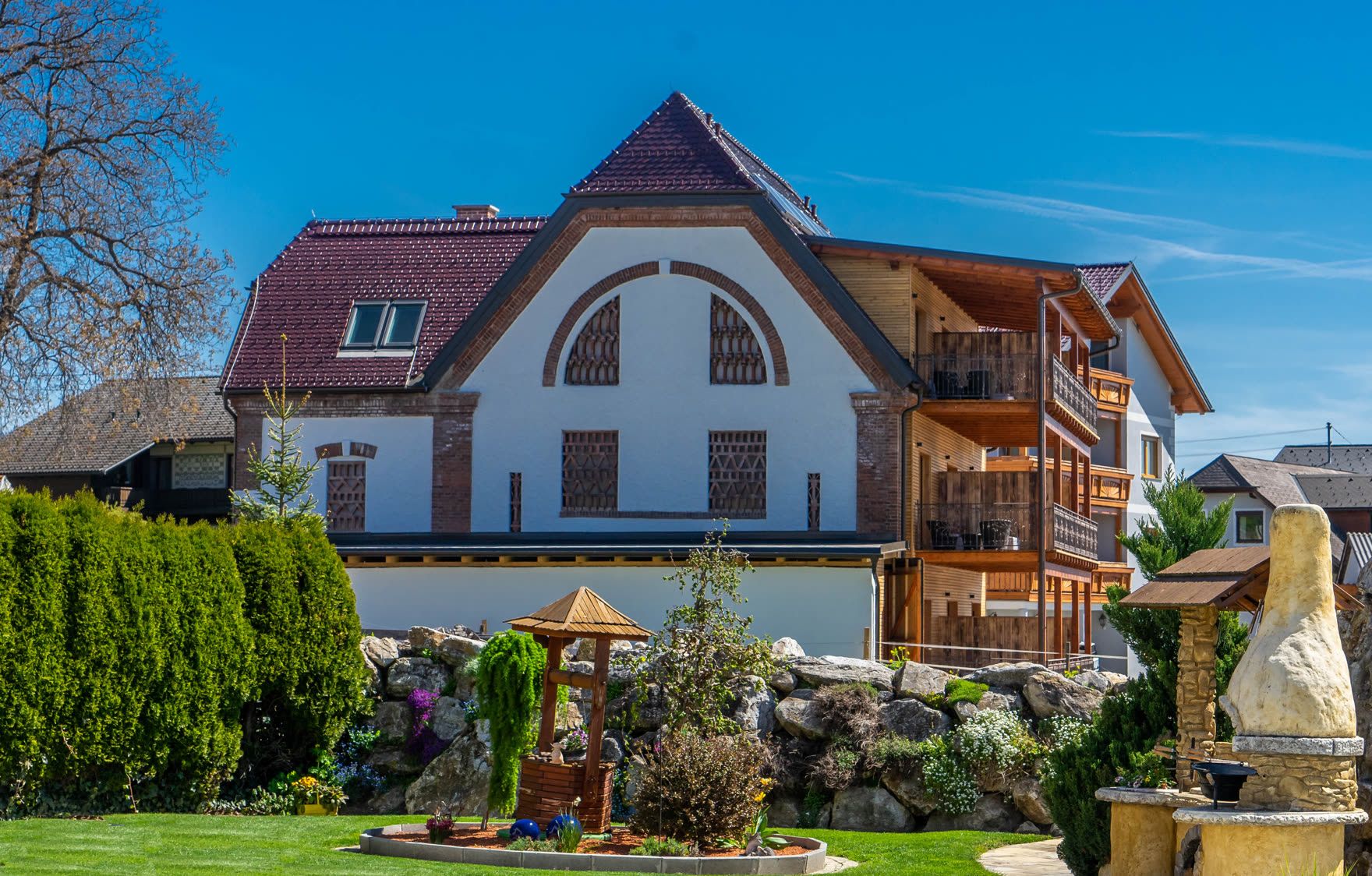 Der Stadl mit dem großen Rundbogengiebel und dem Steingarten davor