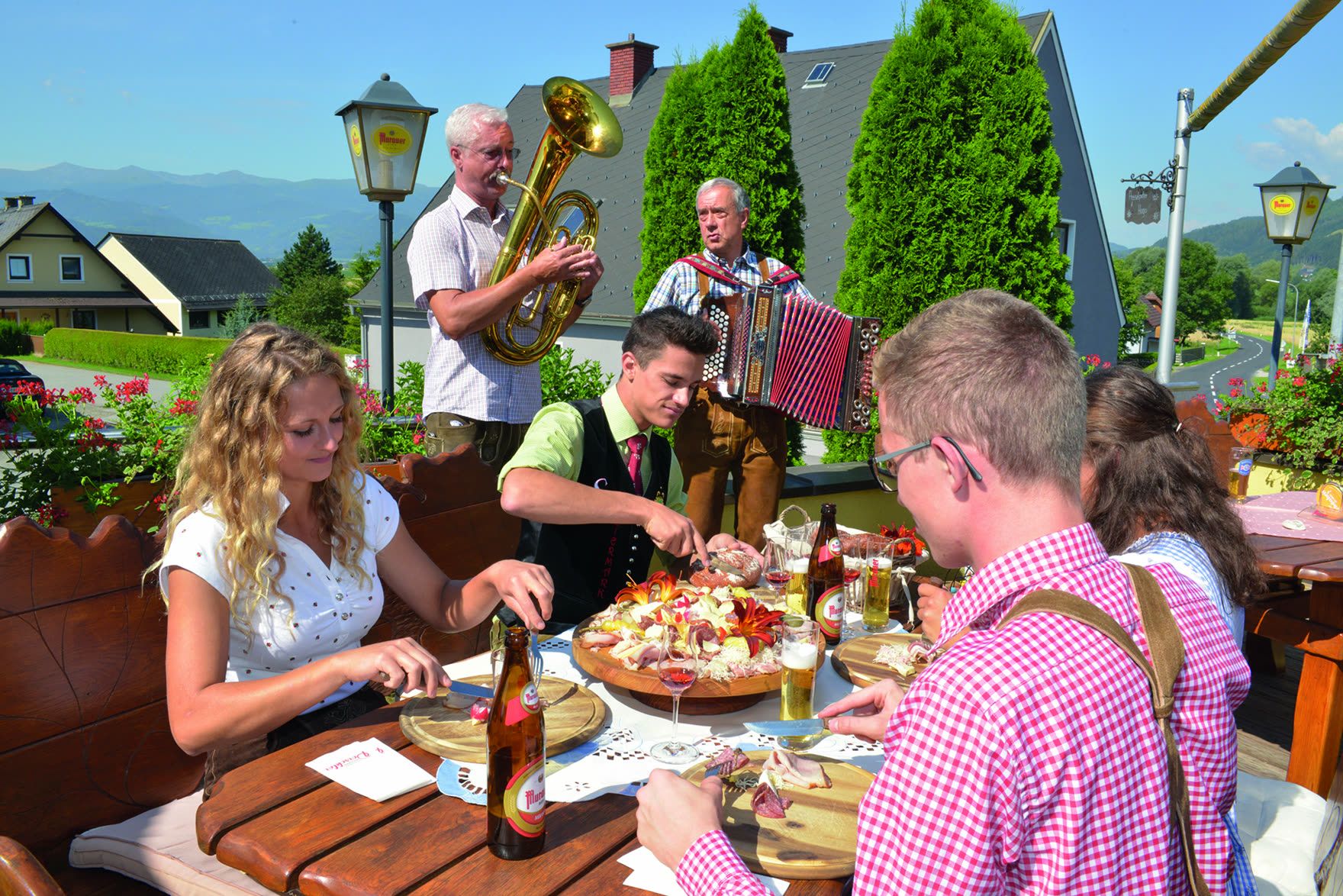 Gäste beim Essen auf der Terrasse, im Hintergrund Musikanten